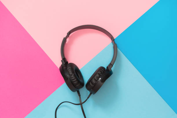 Modern style black headphones on pink blue background.