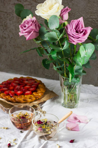 Dining table with flowers, herbal tea and strawberry pie, rustic style