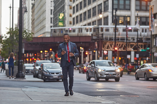 Smiling executive using smart phone on city street
