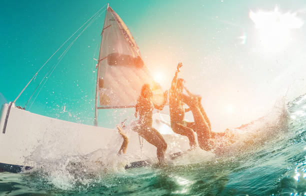 feliz amigos loucos, mergulho de barco à vela no mar - jovens pulando dentro oceano em férias de verão - foco principal em homem de centro - viajar e divertido conceito - distorção de lente olho de peixe - river swimming women water - fotografias e filmes do acervo