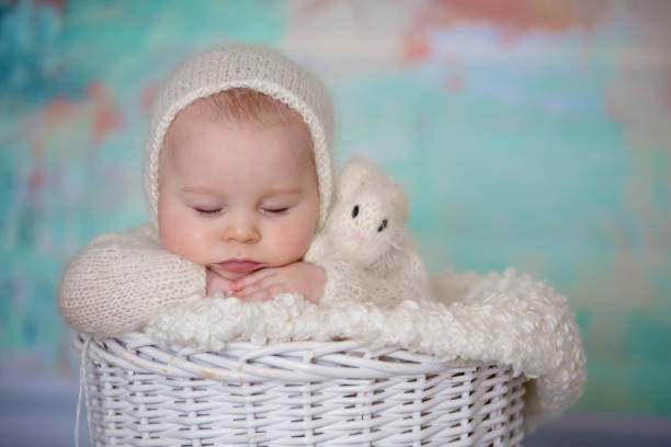 istock Little cute baby boy, dressed in handmade knitted white teddy bear overall, sleeping 924808480