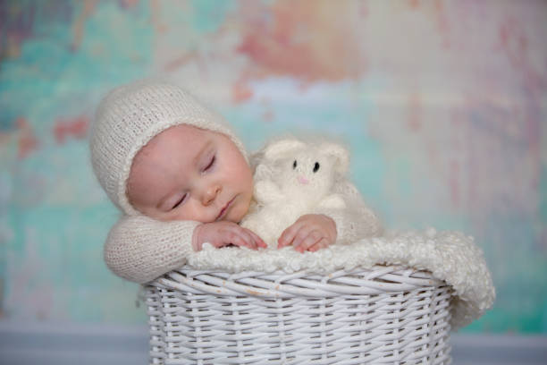 istock Little cute baby boy, dressed in handmade knitted white teddy bear overall, sleeping 924809570