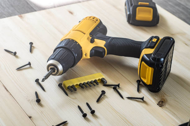 yellow screwdriver on a wooden table, screws, a set of bits.