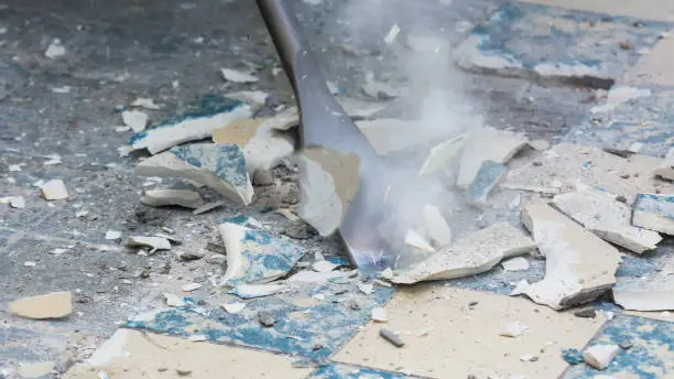 Close-up of a chisel from demolition hammer, fragments of ceramic tiles, dust and small sparks