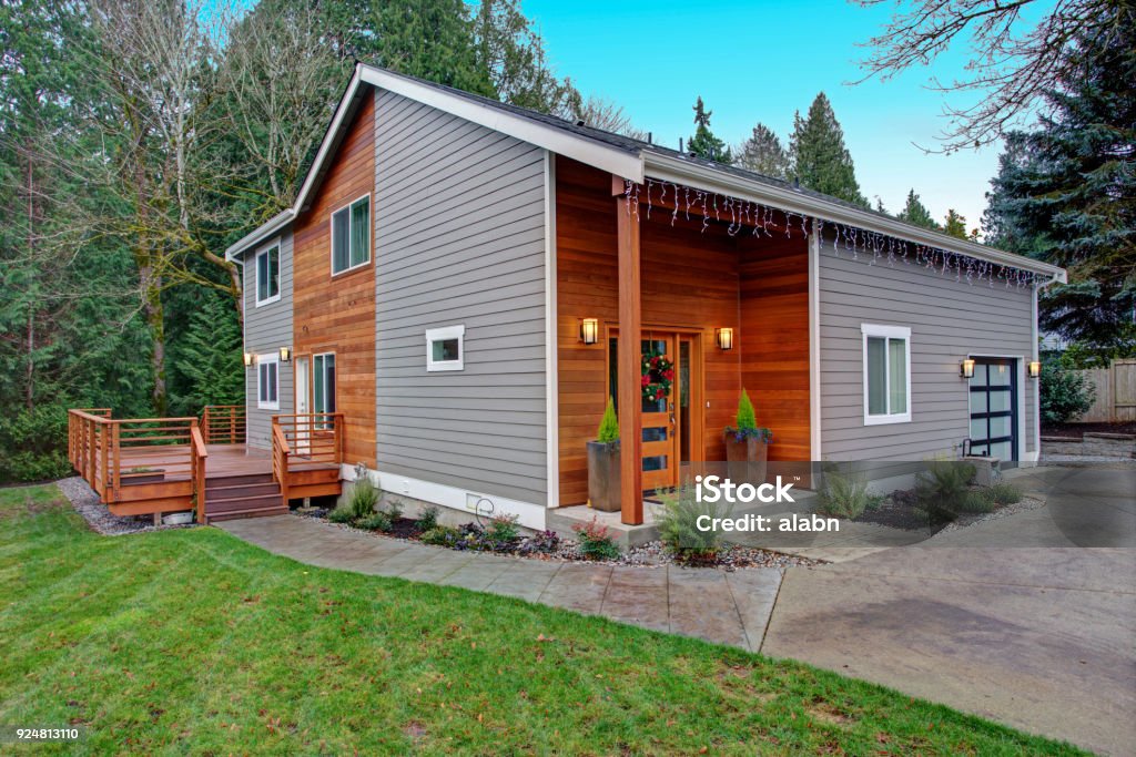 Charming newly renovated home exterior with mixed siding Charming newly renovated home exterior, natural wood siding and grey siding help to encrease curb appeal. House Stock Photo
