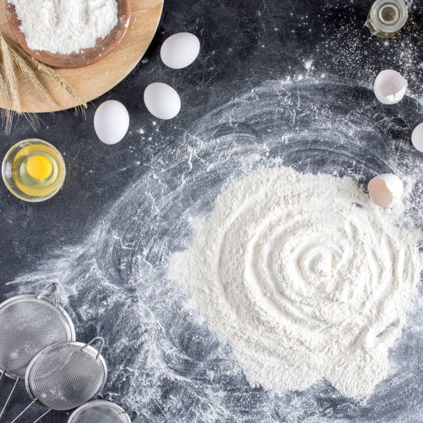 vista dall'alto di setacci disposti, uova crude e farina sul tavolo scuro - baking flour ingredient animal egg foto e immagini stock