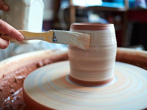 production process of pottery. Application of glaze brush on ceramic ware.