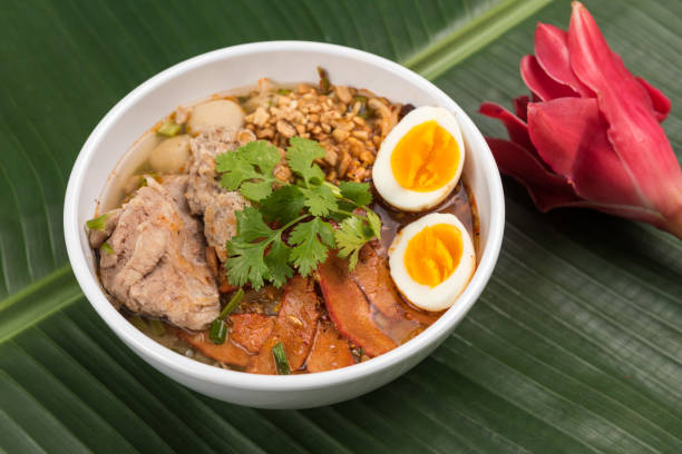 istock Spicy noodle soup with pork and egg in bowl on banana leaf 924825836