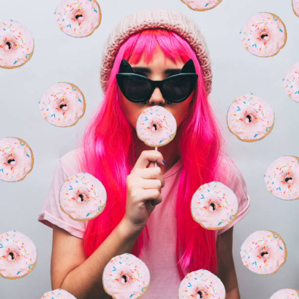 la jeune fille à lunettes et chapeau bonnet rose mange un donut - image created 1990s photos et images de collection