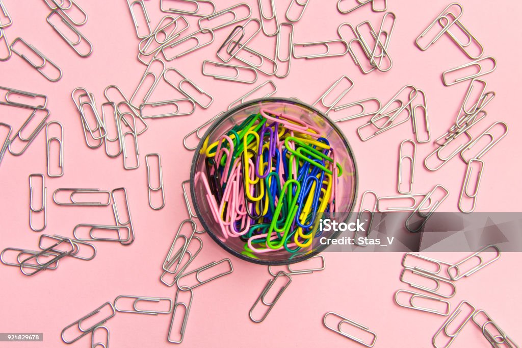 The concept of order and chaos. Chaotic scattered silvery paper clips on pink background and ordered stacked multicolored paper clips. The concept of organized society Balance Stock Photo