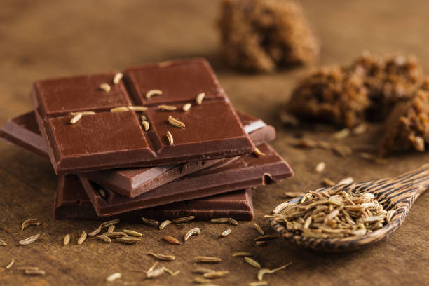 istock Chopped bitter chocolate in stack with cumin seeds on wooden background 924832702