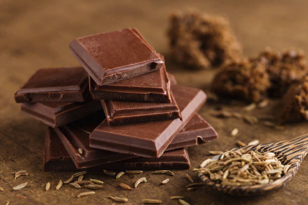 istock Chopped bitter chocolate in stack with cumin seeds on wooden background 924832724