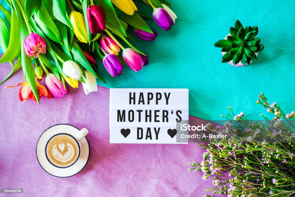 Happy mother's day written in lightbox with spring flowers from above Shot from above as flatlay with happy mother's day message written on light box with coffee and colorful tulips and flowers Mother's Day Stock Photo