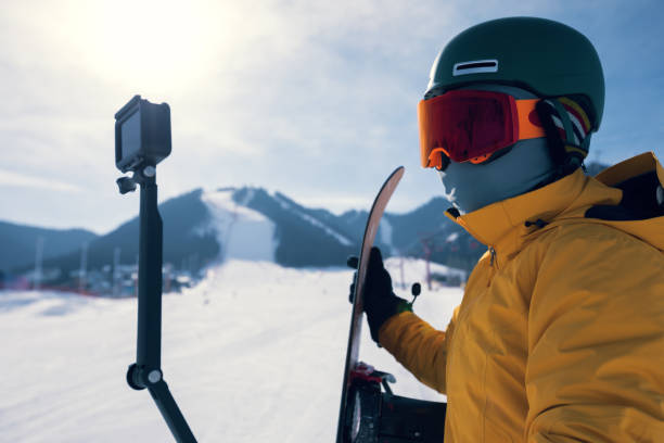 jeden snowboardzista używa kamery akcji robiąc selfie na stoku zimowego ośrodka narciarskiego - sports equipment winter day sunlight zdjęcia i obrazy z banku zdjęć