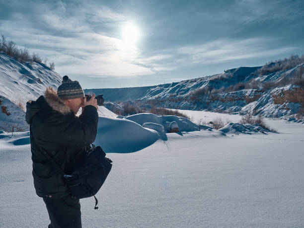 istock A man with a camera in his hands examines the plain covered with snow. 924841680