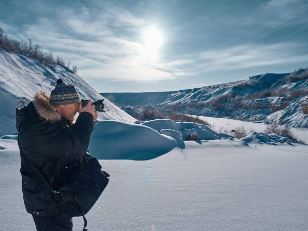 istock A man with a camera in his hands examines the plain covered with snow. 924841686
