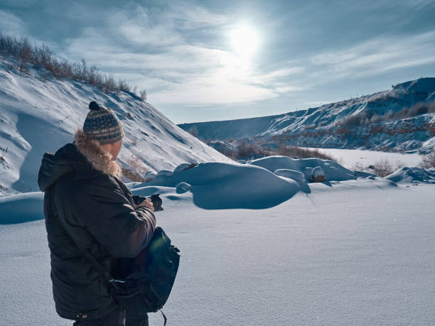 istock A man with a camera in his hands examines the plain covered with snow. 924841690