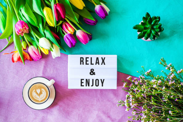 istock Relax & Enjoy written in lightbox with spring flowers from above 924841780