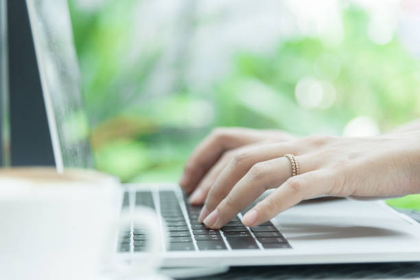 istock Asian woman hands and married ring has touching and typing on laptop computer with blurred coffee, computer and view outside window. 924850262