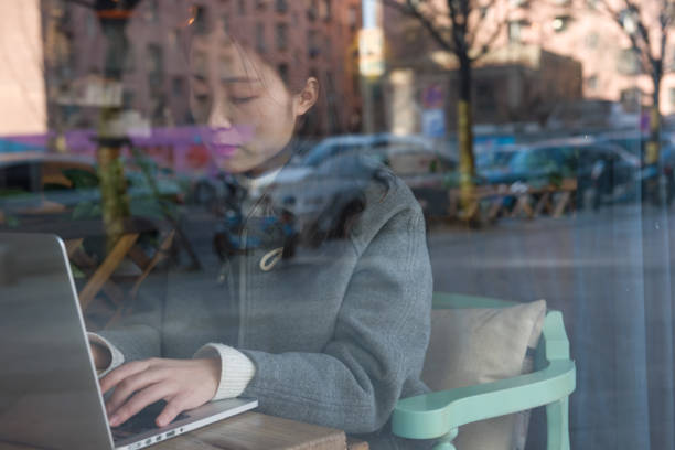 istock Woman with coffee, laptop and mobile phone looking through window 924853200