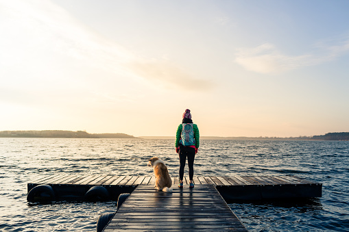 Woman with dog enjoy sunrise at lake, backpacker