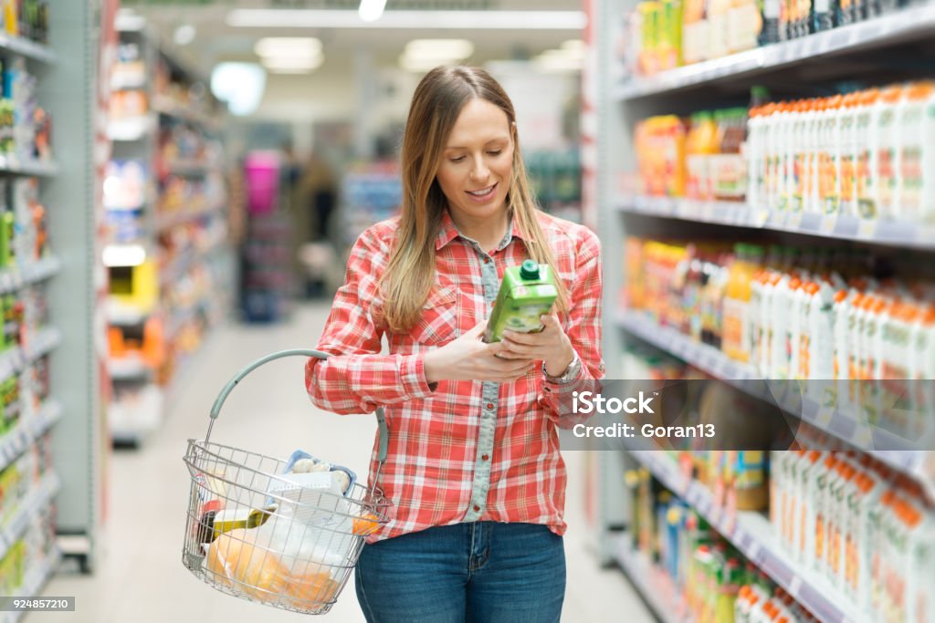 Young woman shopping groceries Smiling woman shopping for juice in supermarket Shopping Stock Photo