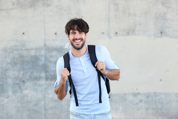 istock handsome man with bag smiling against wall 924861442