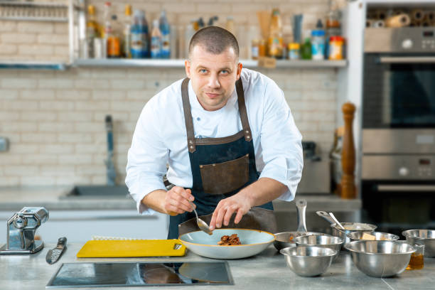 istock Caucasian chef putting food on a plate in a restaurant kitchen. 924862552