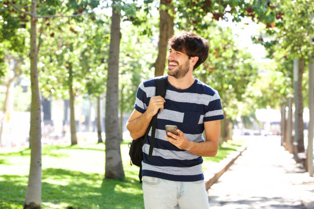istock young man walking with cellphone and bag in park 924867074