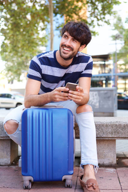 istock cool travel man sitting with suitcase and mobile phone 924867122