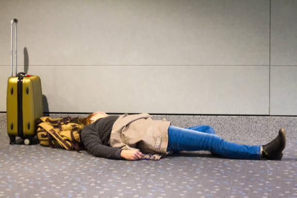 Bad Trip: Woman sleeping on airport floor on a long layover, luggage around.
