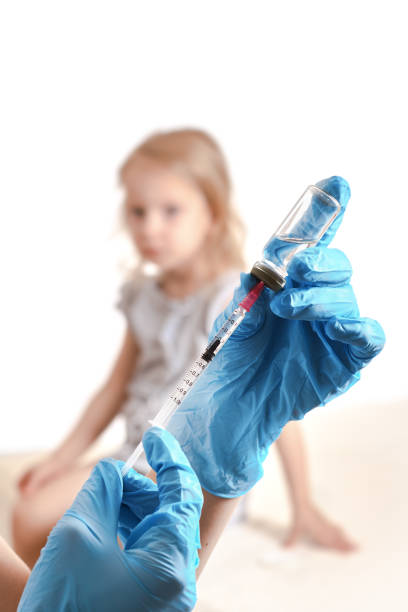 vaccination concept. doctor holding a syringe with a liquid inside next to a girl arm. blurred background of a girl. - vacinate imagens e fotografias de stock