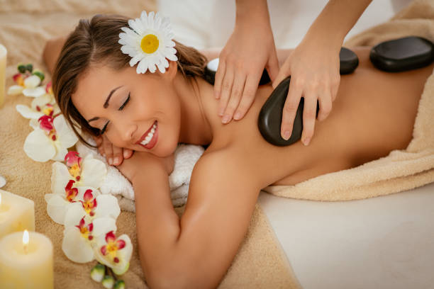 Lastone Therapy Beautiful woman enjoying during a back massage with warm stones at a spa. hot stone massage stock pictures, royalty-free photos & images