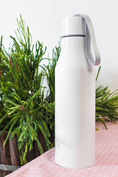 Steel bottle with rope on kitchen table background. Blank drink container for design.