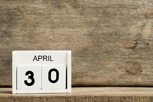 White block calendar present date 30 and month April on wood background