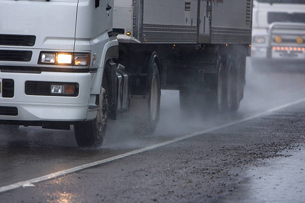 Trucks drive along a wet highway Two trucks move along a rainy road, spray coming out from the side around the tires. Lots of copy space. truck rain stock pictures, royalty-free photos & images