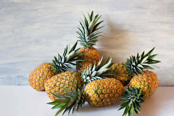 istock Ripe pineapples on white wooden background 924893810