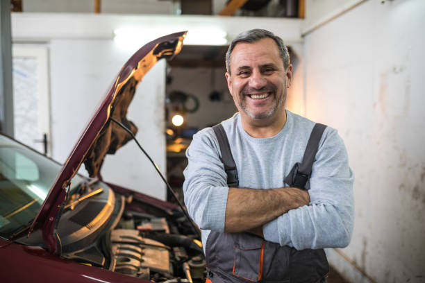 Happy on his job Senior mechanic posing to a camera at car service,smiling with arms crossed mechanic photos stock pictures, royalty-free photos & images