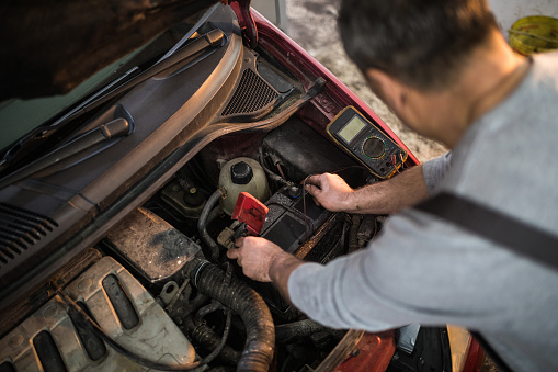 Senior unrecognizable mechanic working at car service,fixing broken car