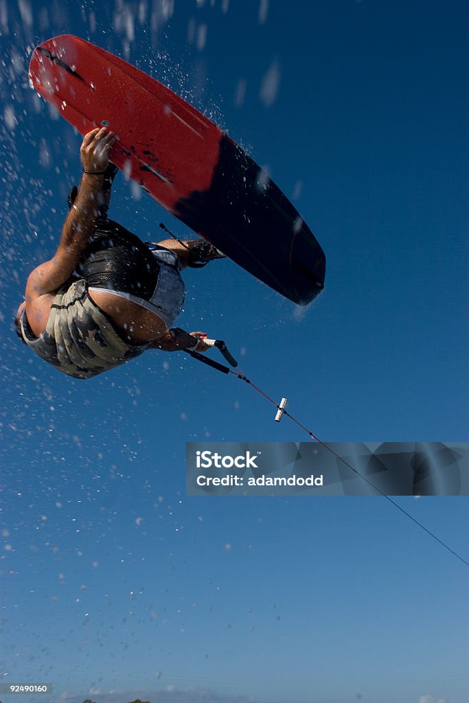 Wakeboarder shot from under flies through the air A wakeboarder, 20 to 30 year old,  shot from underneath with a clear blue sky background. Lots of copy space on the blue sky. Wakeboarding Stock Photo