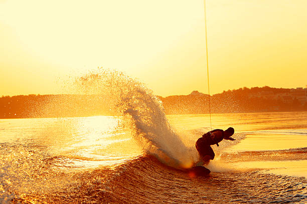 wakeboarder вас на пятке расположена на закате - wakeboarding стоковые фото и изображения