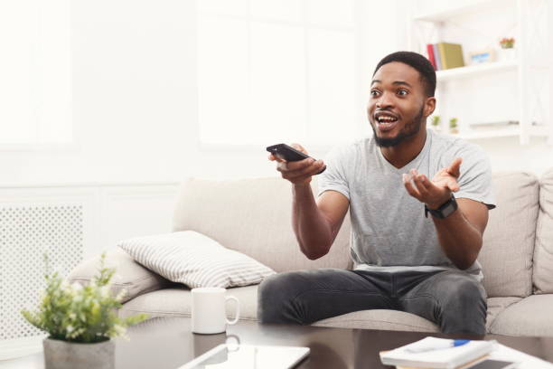 istock Emotional young man watching tv at home 924906392