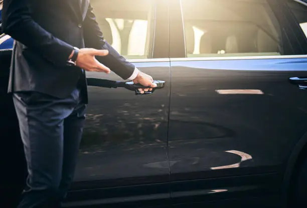 Cropped shot of a well dressed and unrecognizable man opening a car door