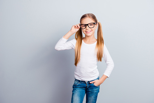 Beauty positivity emotional expressing blonde hair dream profession occupation concept. Portrait of beautiful adorable dreamy girl touching glasses keeping hand in pocket isolated on gray background