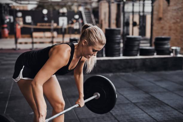 istock Fit young woman lifting heavy weights alone in a gym 924914598