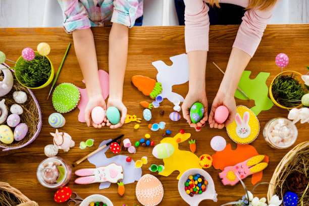 istock Top view horizontal portrait of attractive, beautiful, colorful handmade easter objects, subjects, things, baked cookies laying on wooden table and hands showing painted, decorated small, little eggs 924928198