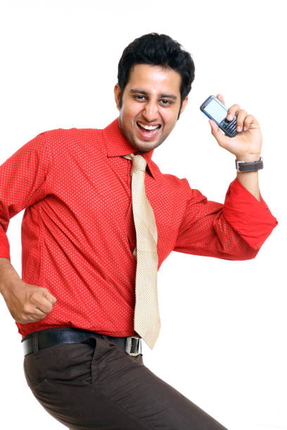 Cheerful young businessman cheering with mobile phones on white.