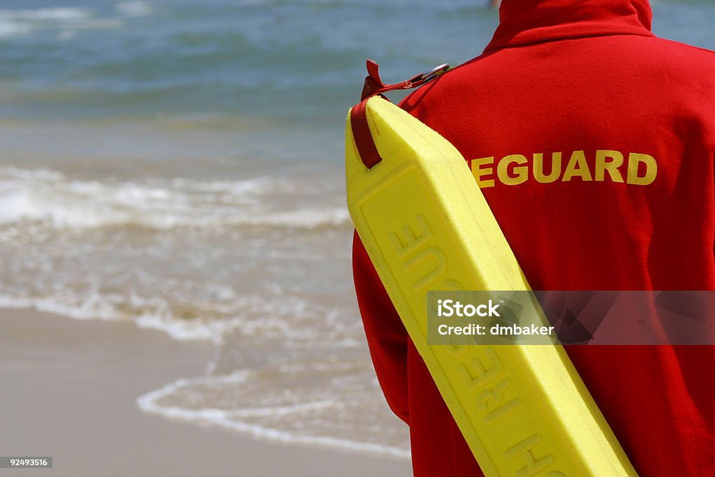 Baywatch Lifeguard With Float At A Beach A lifeguard complete with rescue float monitors their beach Lifeguard Stock Photo