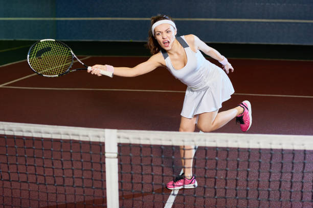 wilde frau tennisspielen vor gericht - indoor tennis flash stock-fotos und bilder