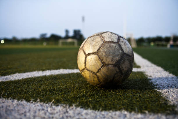 緑の芝生に古い革製サッカー ボール - soccer field dirty soccer outdoors ストックフォトと画像